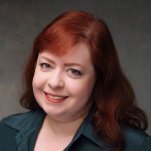 Emily Cotlier, a pleasant redheaded woman smiling at you, wearing a professional teal shirt.